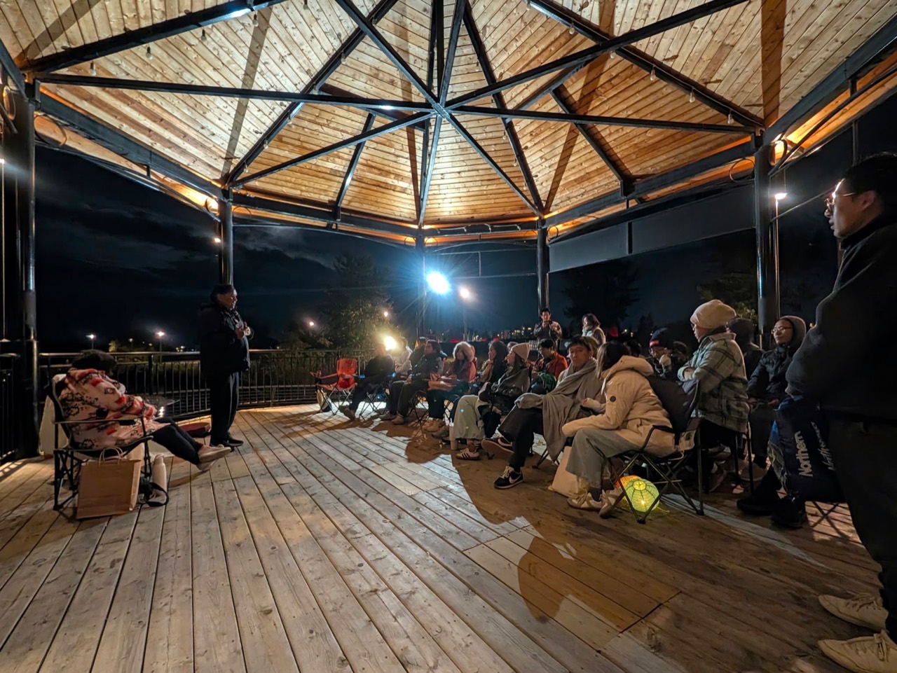 Akşam, dört yanı açık Music Pavilion’da dinleyiciler bir konuşmacıyı dinliyor.